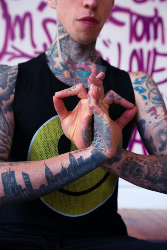man in black shirt with blue and red tattoo on his left hand