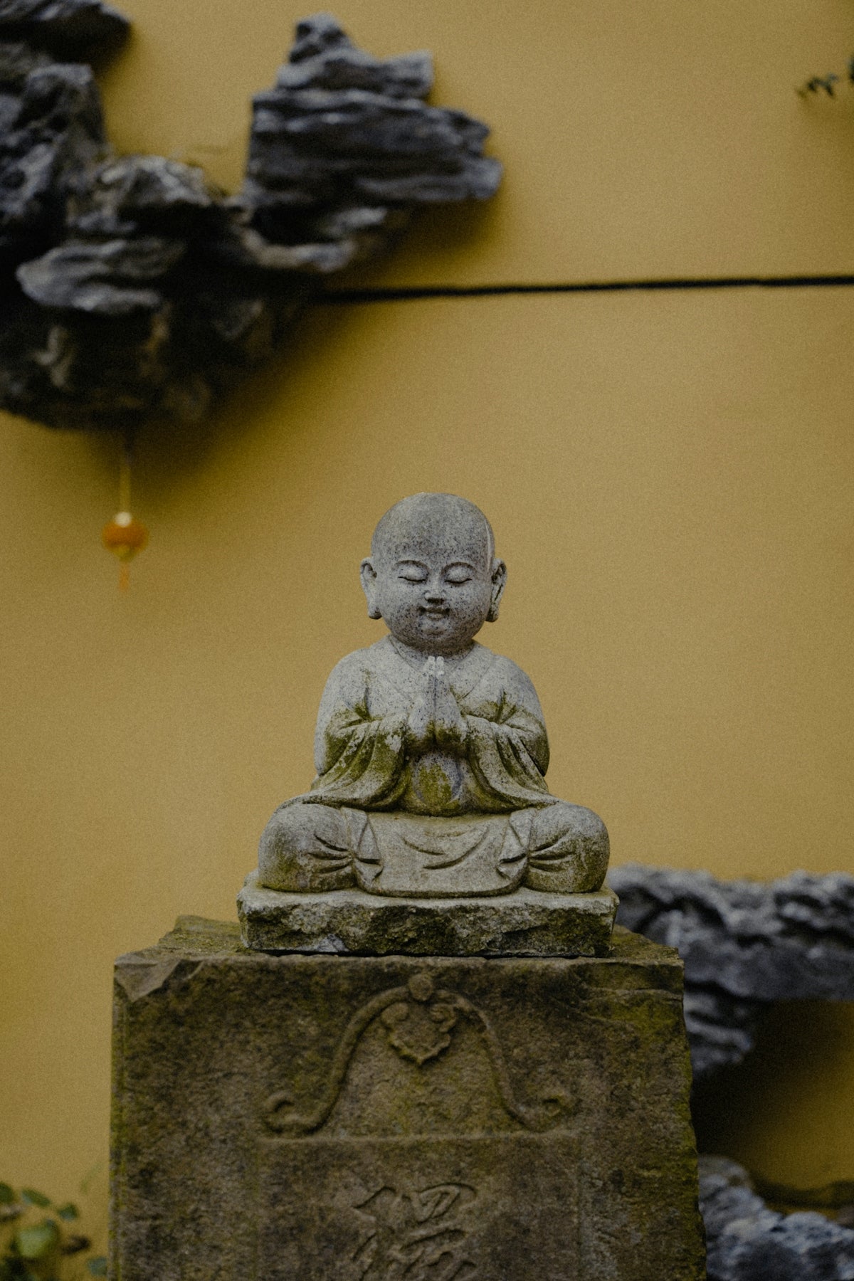 a statue of a buddha in front of a yellow wall